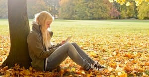 Girl reading under tree in autumn