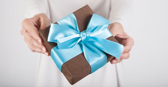 Hands holding gift with blue ribbon