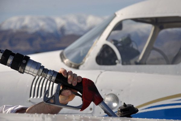 person fueling up a small airplane with Colorado mountains in the background