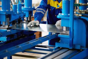 person feeding a metal plate through machining equipment