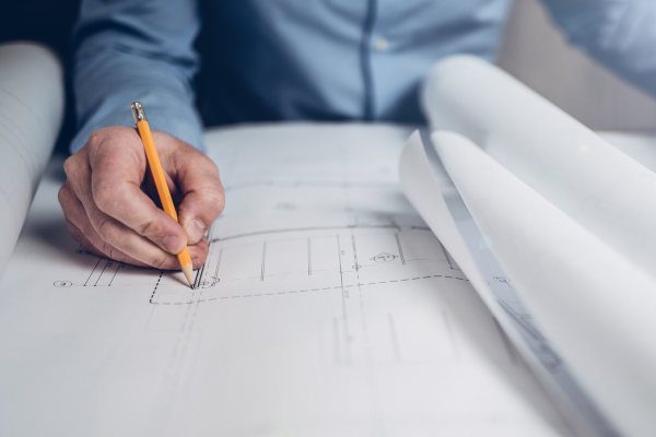 architect drawing building plans with a pencil