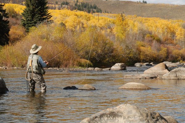person fly-fishing in Western Colorado river in the fall