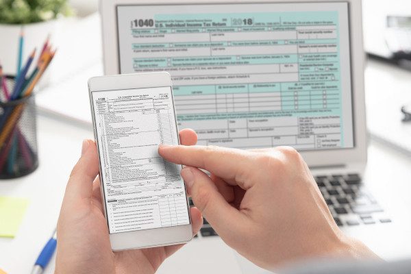 close up of person filing tax return documents on mobile devices
