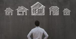 man staring at chalkboard drawing of multiple houses
