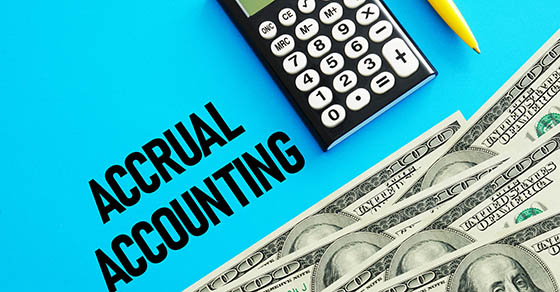 A blue background | half a calculator and pen are shown | Below the calculator are five, one hundred dollar bills | by them it says Accrual Accounting | DWC CPAs and Advisors | business consulting, tax services, audit and assurance, estate and gift planning, wealth management, bookkeeping, outsourced accounting | Grand Junction CO | Montrose CO | Glenwood Springs CO