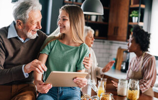 An elderly man talking with his daughter | the daughter is holding a tablet | she is looking at a tablet with her health care decisions