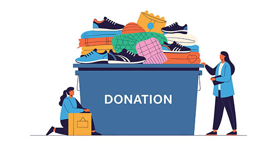 Two people donating clothes and shoes to a donation bin filled with items.