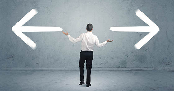 A businessman in doubt, having to shoose between two different choices indicated by arrows pointing in opposite direction concept